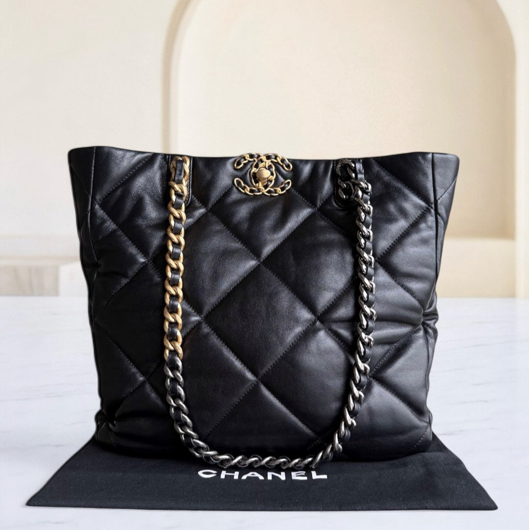 Black quilted Chanel handbag with gold chain on a white surface