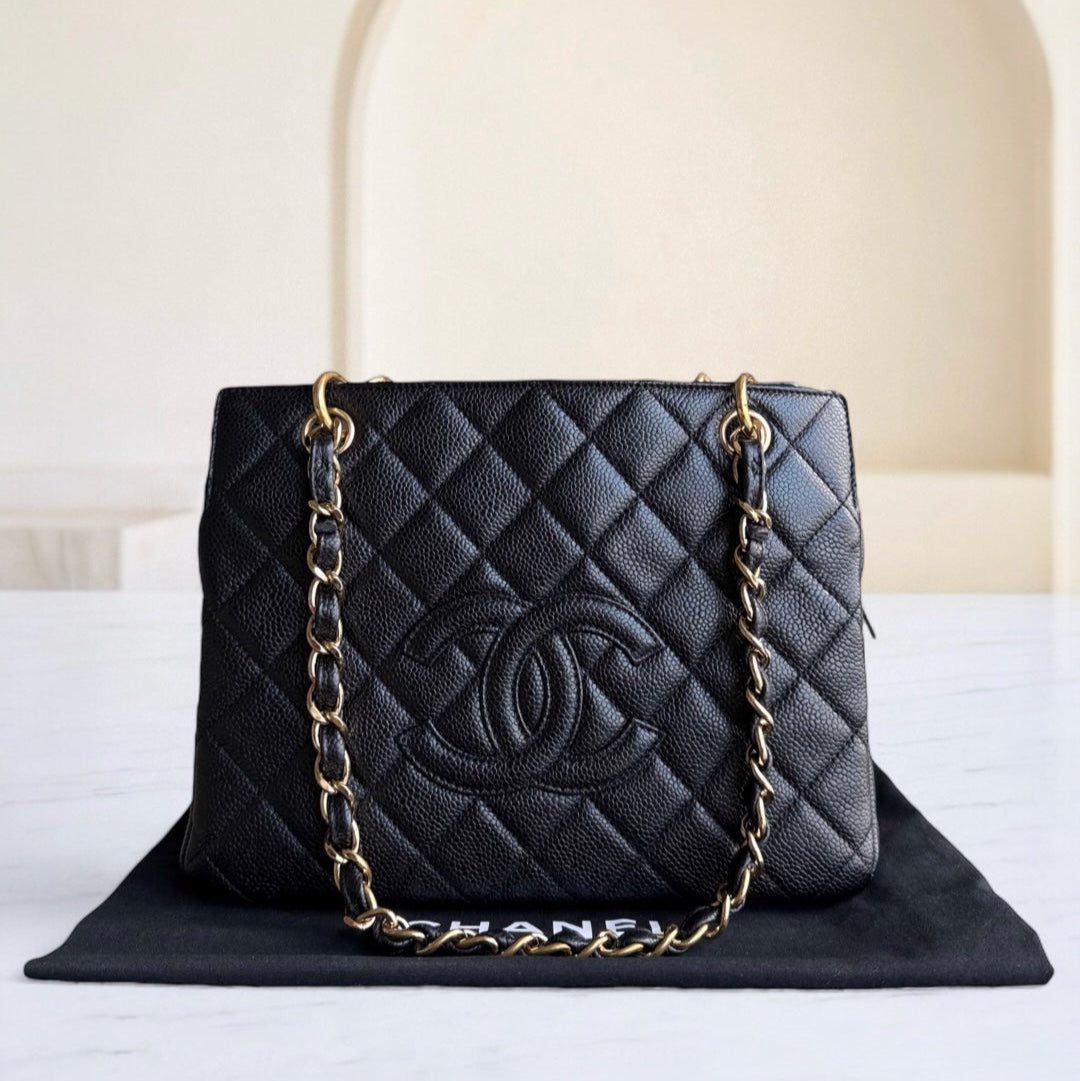 Black quilted handbag with gold chain strap on a white surface