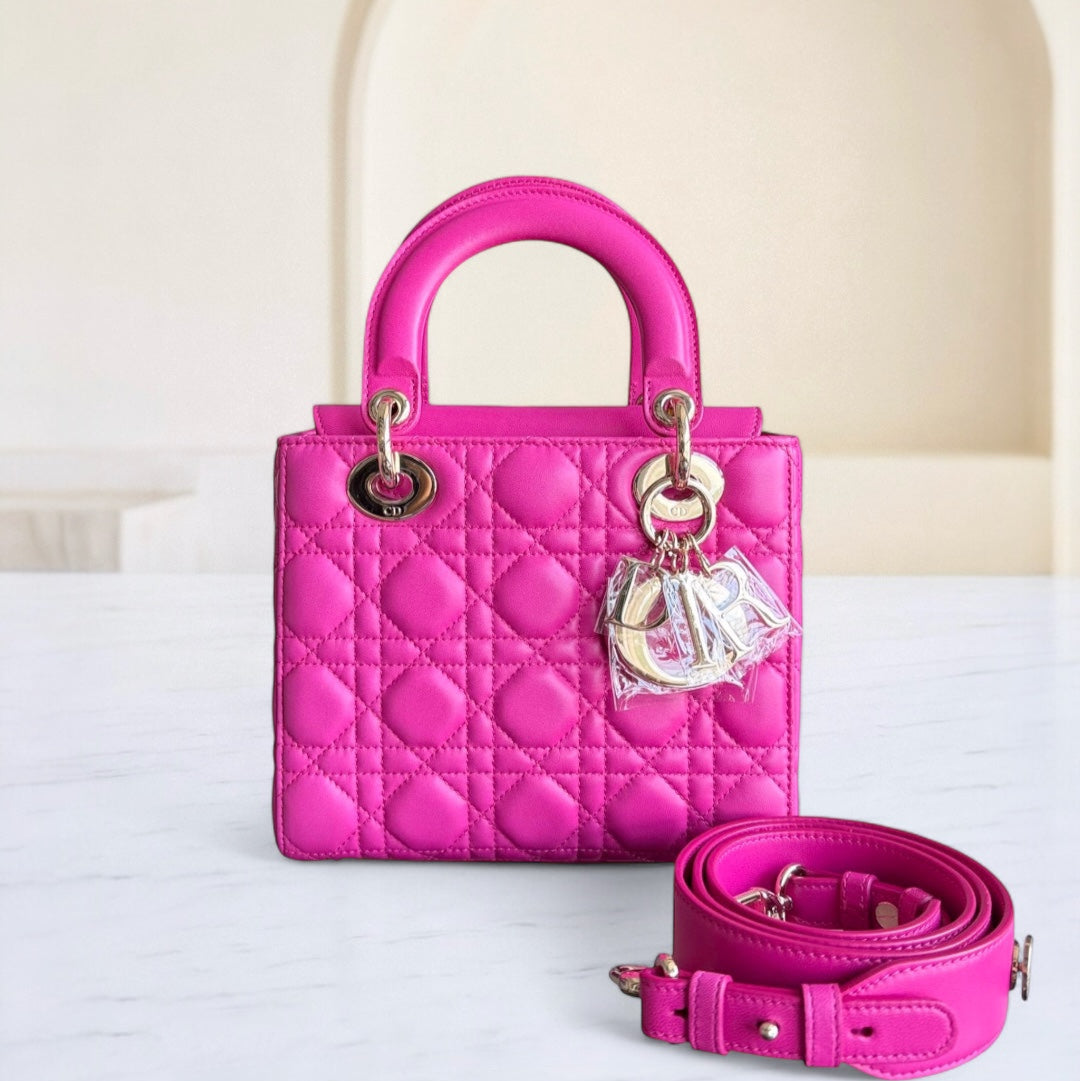 Pink handbag with matching strap on a white surface