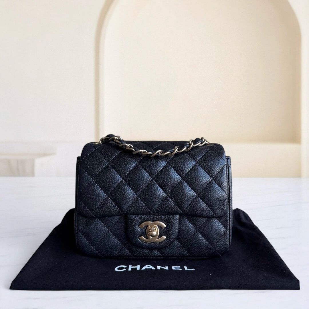 Black quilted Chanel handbag on a black mat with a white background