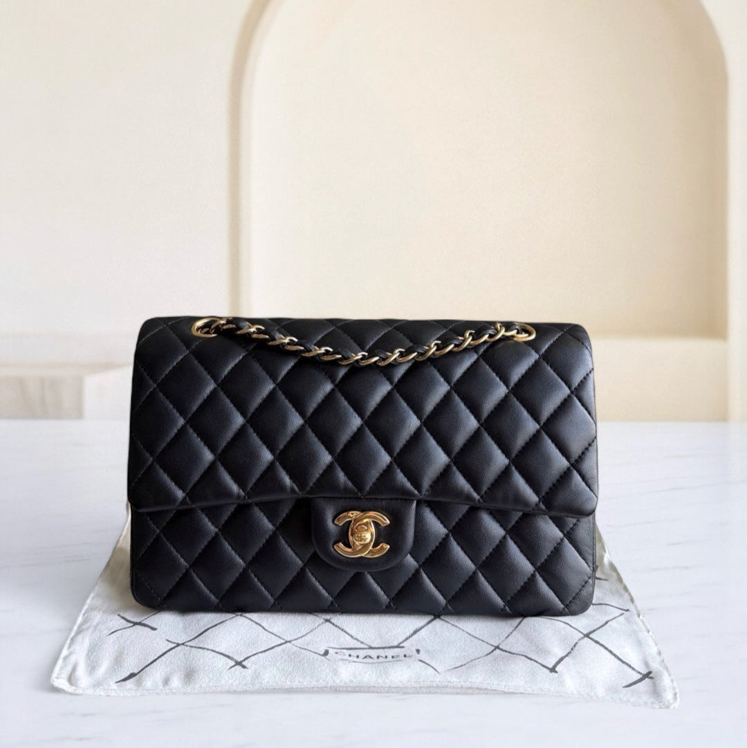 Black quilted handbag with gold chain on a white surface