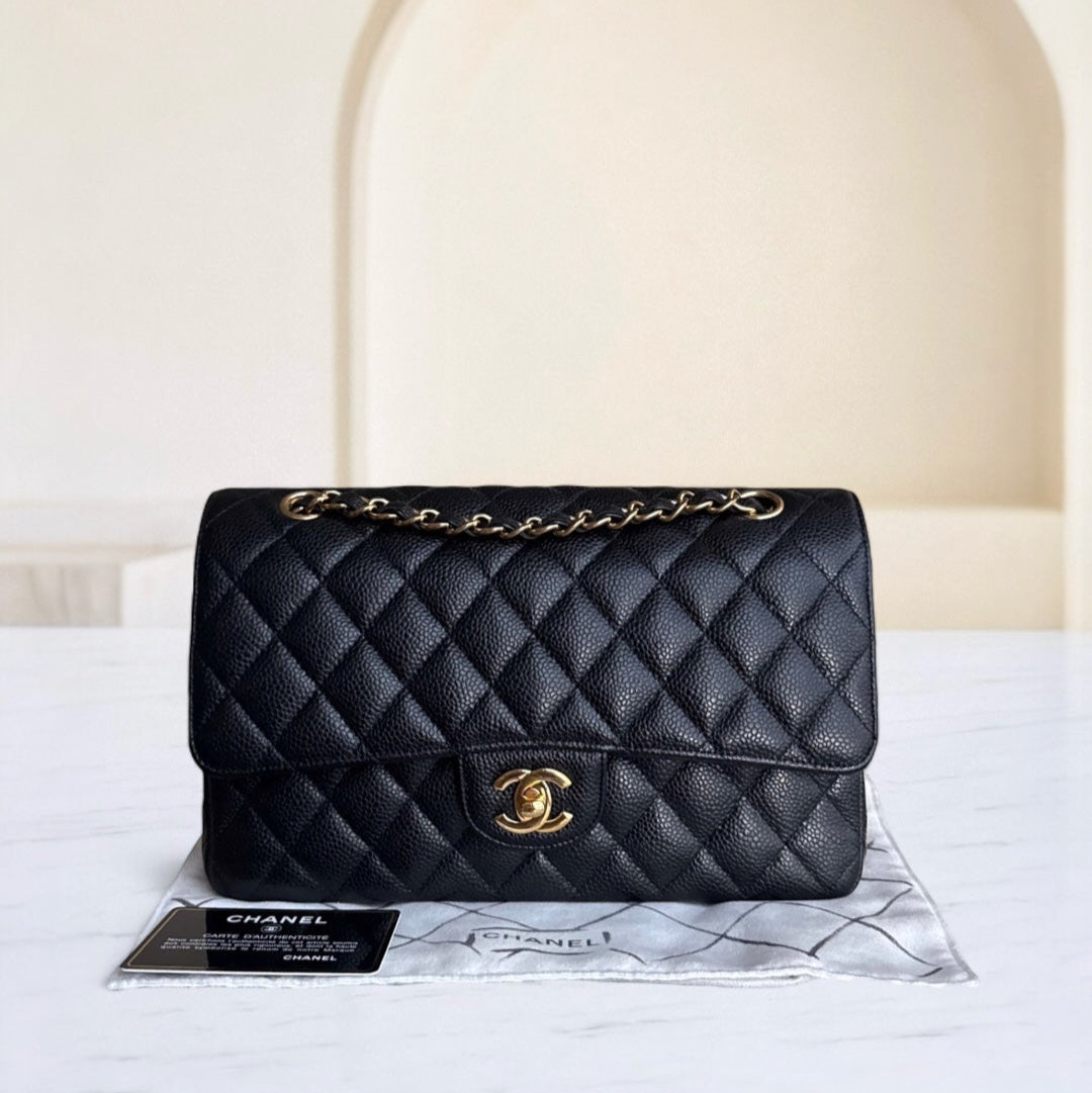 Black quilted Chanel handbag on a white surface with a neutral background