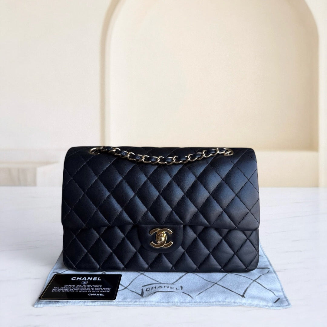 Black quilted Chanel handbag on a white surface with a beige background