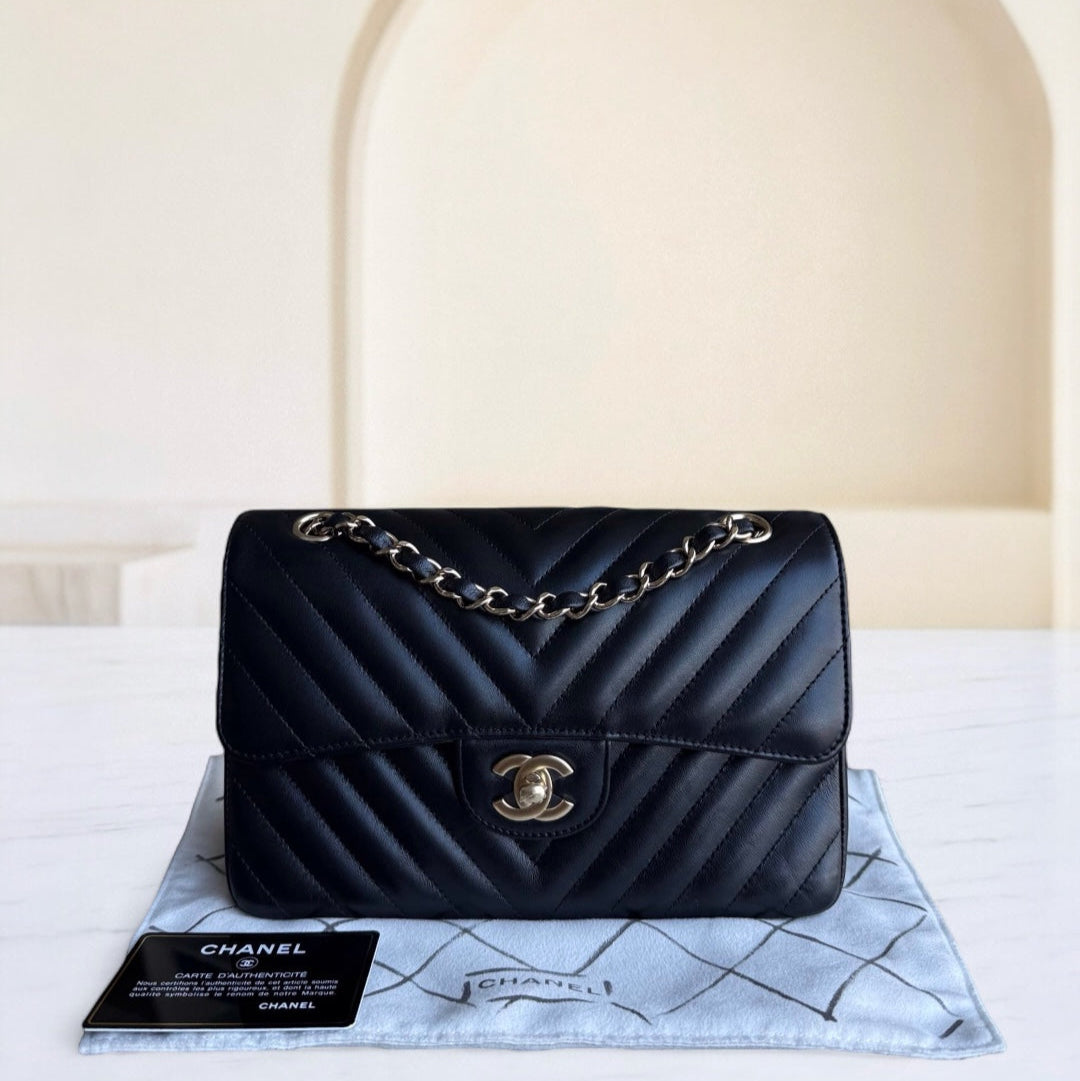 Black Chanel handbag with gold chain on a white surface