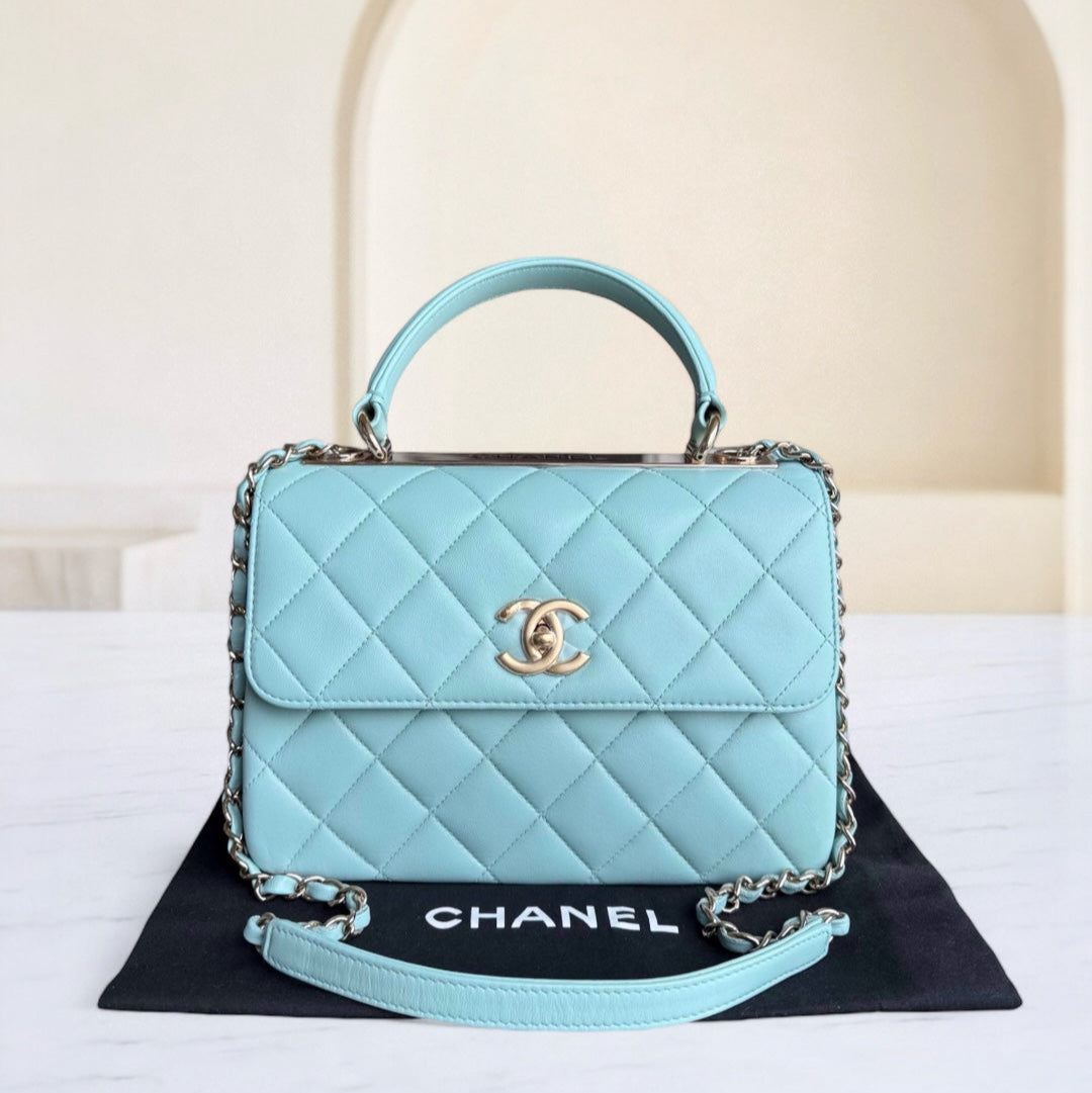 Light blue quilted Chanel handbag on a black mat with a white background