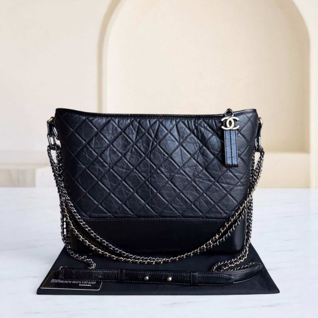 Black quilted handbag with chain detail on a white surface