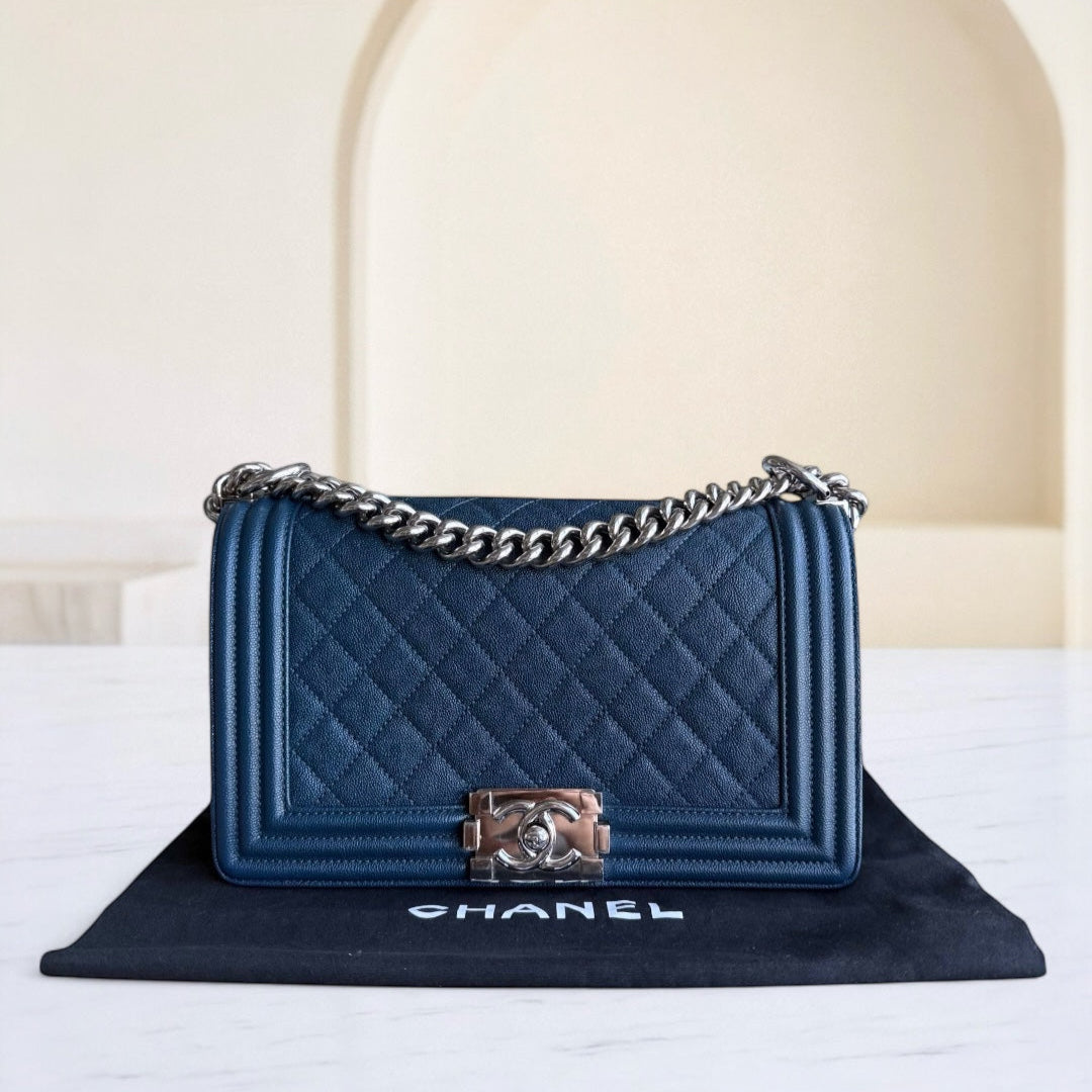 Blue quilted handbag with silver chain and clasp on a Chanel branded mat.