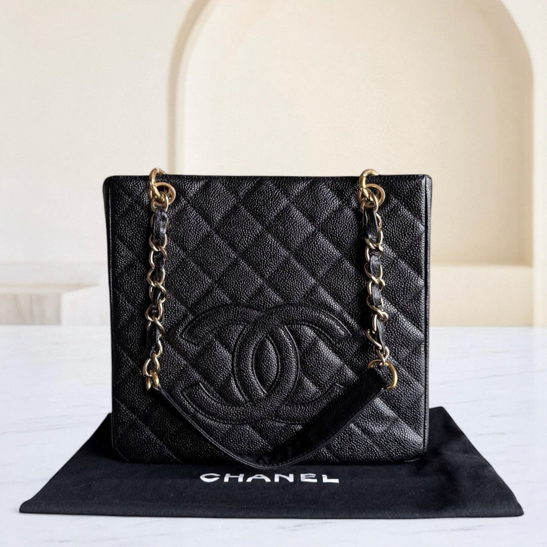Black quilted Chanel handbag with gold chain on a white surface
