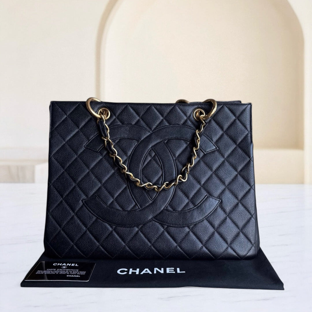 Black quilted Chanel handbag with gold chain on a white surface
