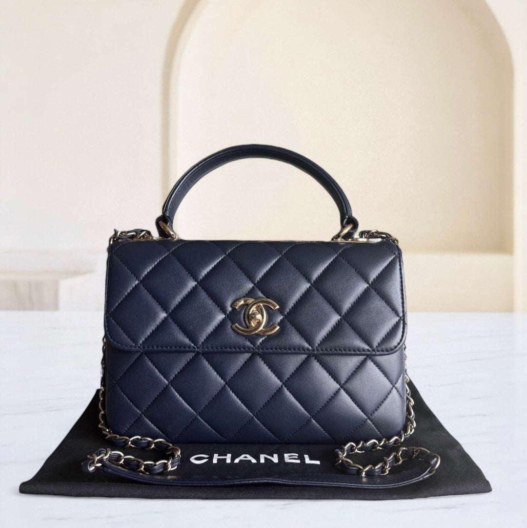 Navy blue quilted Chanel handbag on a white surface with a beige background
