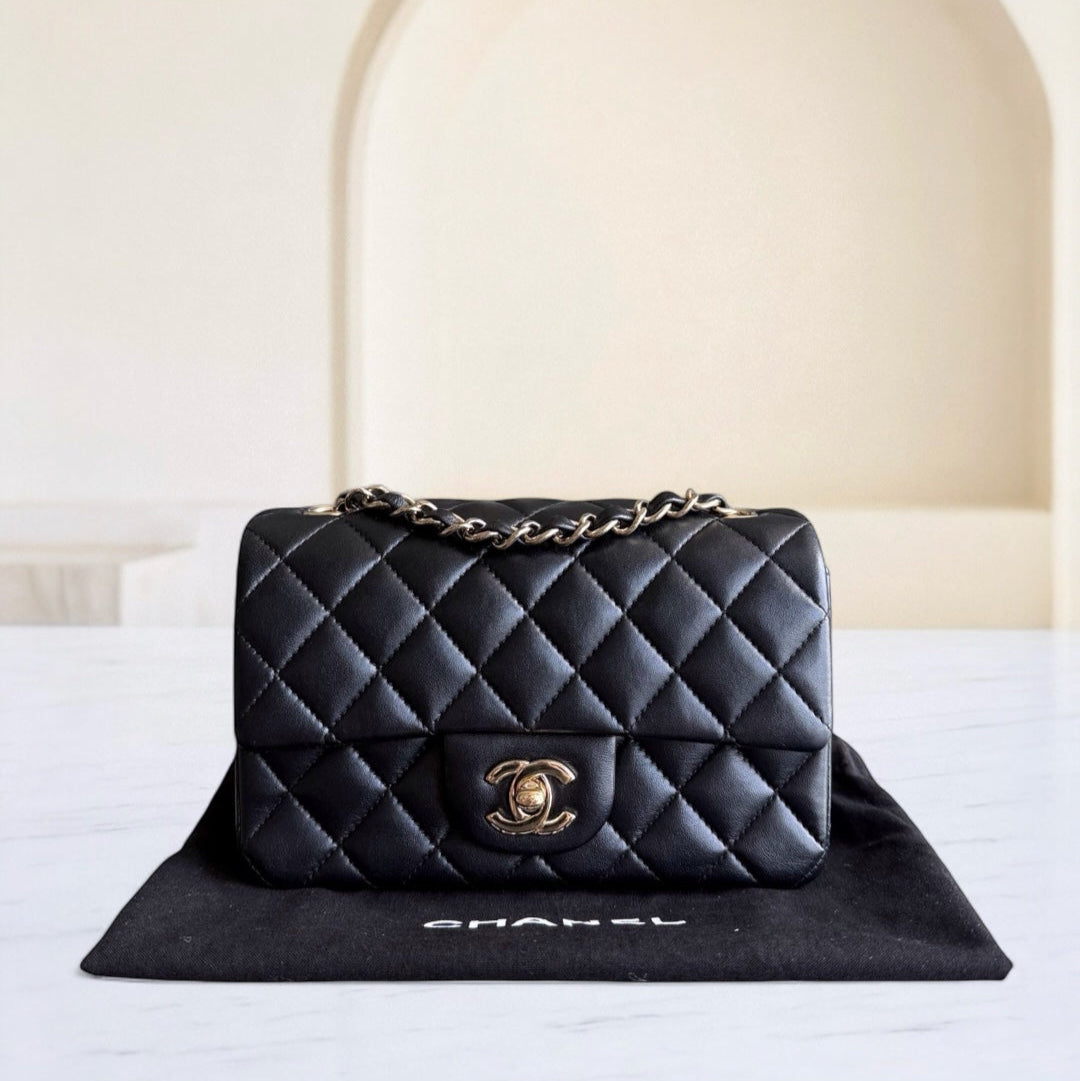 Black quilted Chanel handbag on a white surface with a blurred background