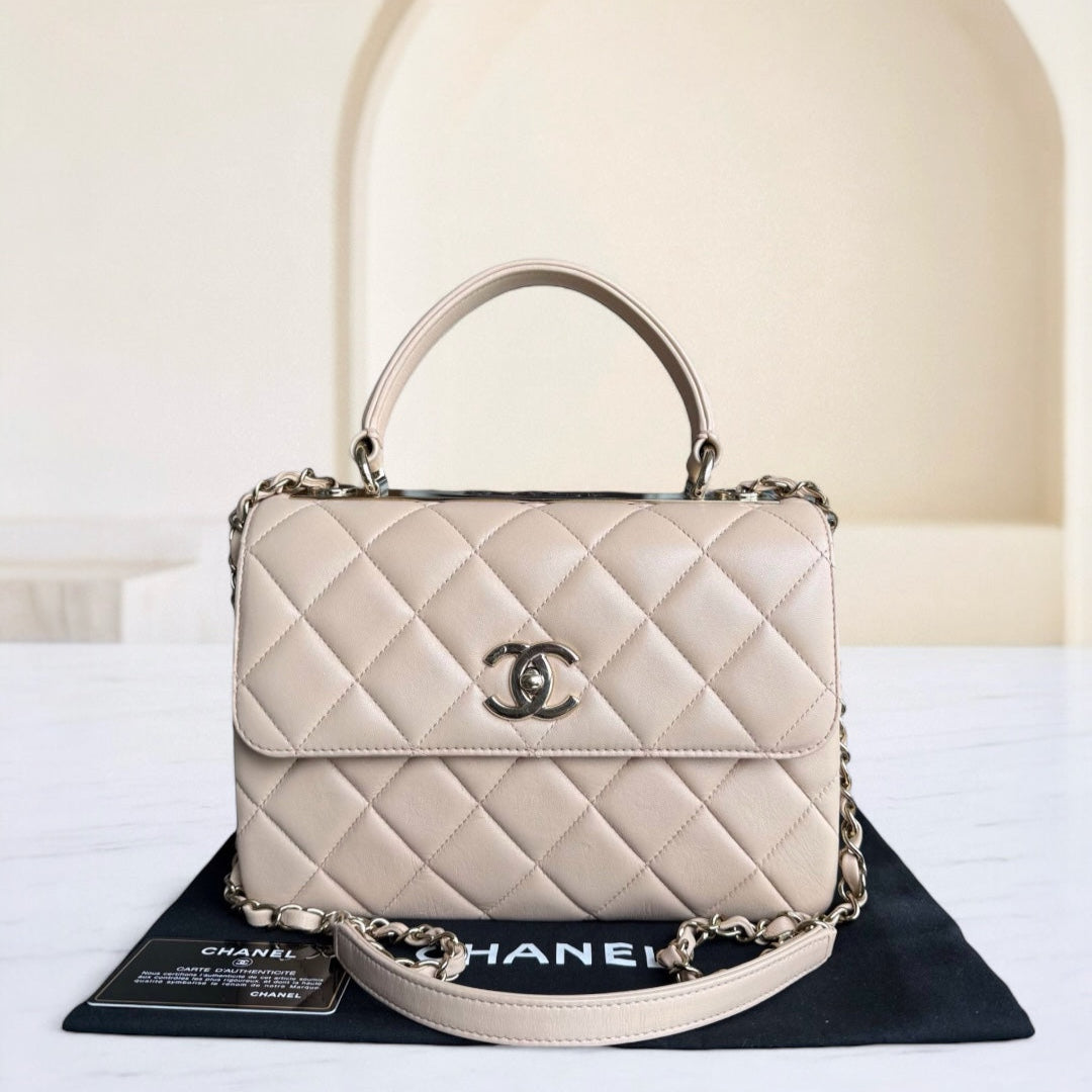 Beige quilted handbag with Chanel logo on a black stand against a white background