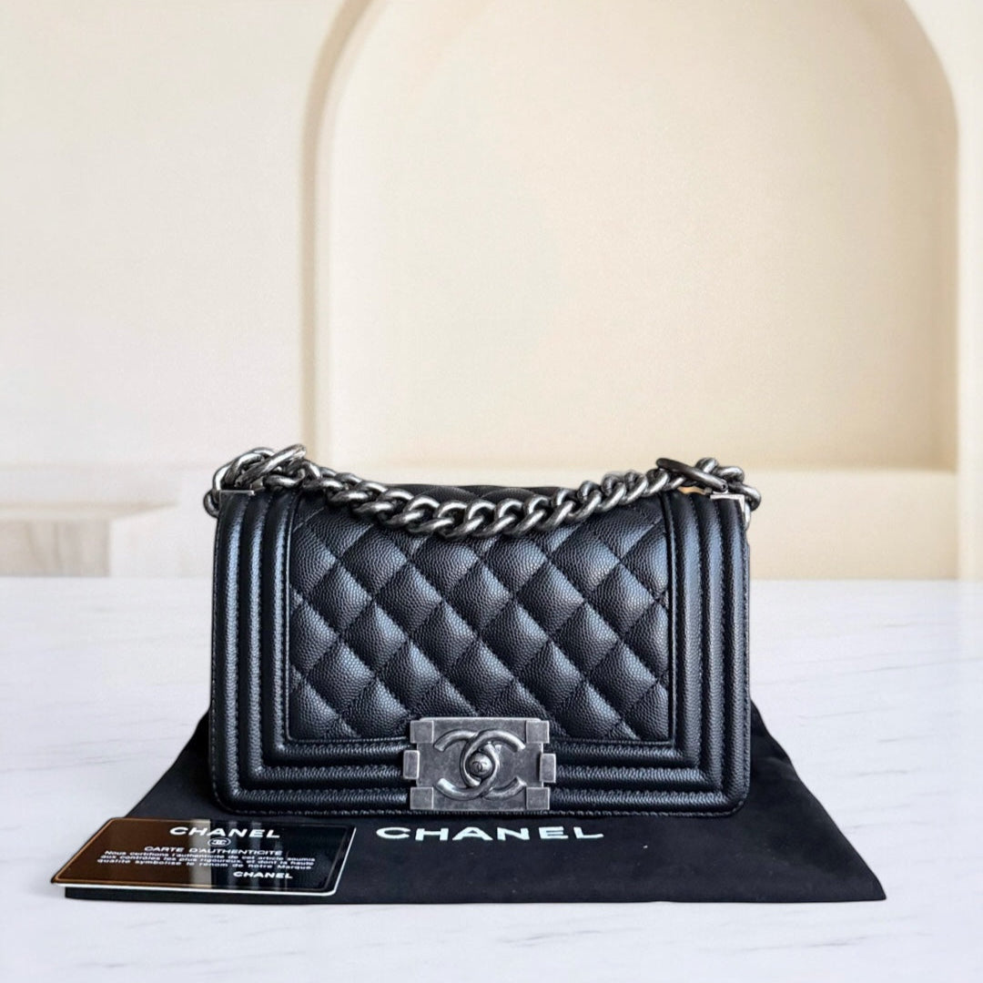 Black quilted Chanel handbag on a white surface with a beige background