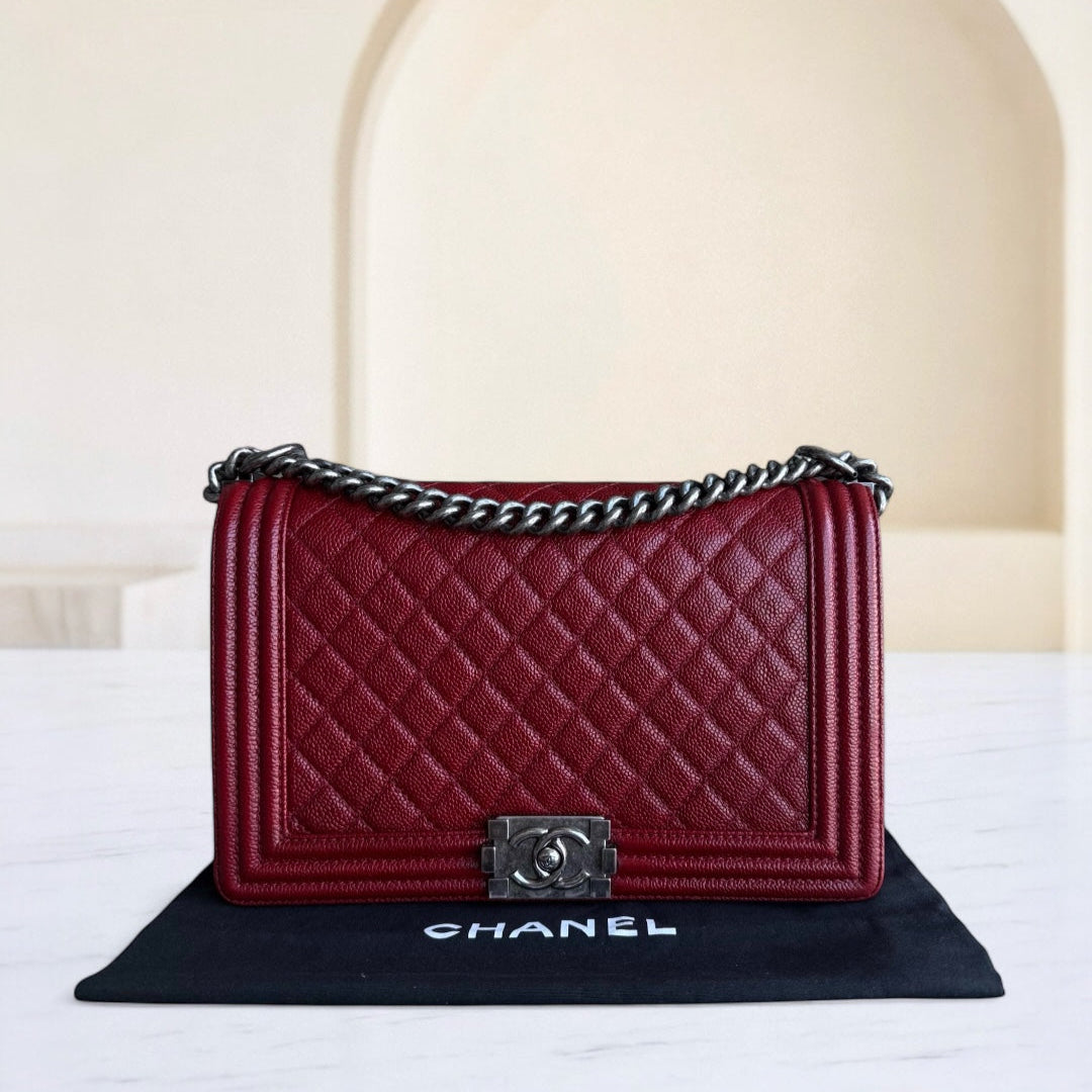 Red quilted handbag with silver chain detail on a black mat with 'Chanel' branding, against a neutral background.