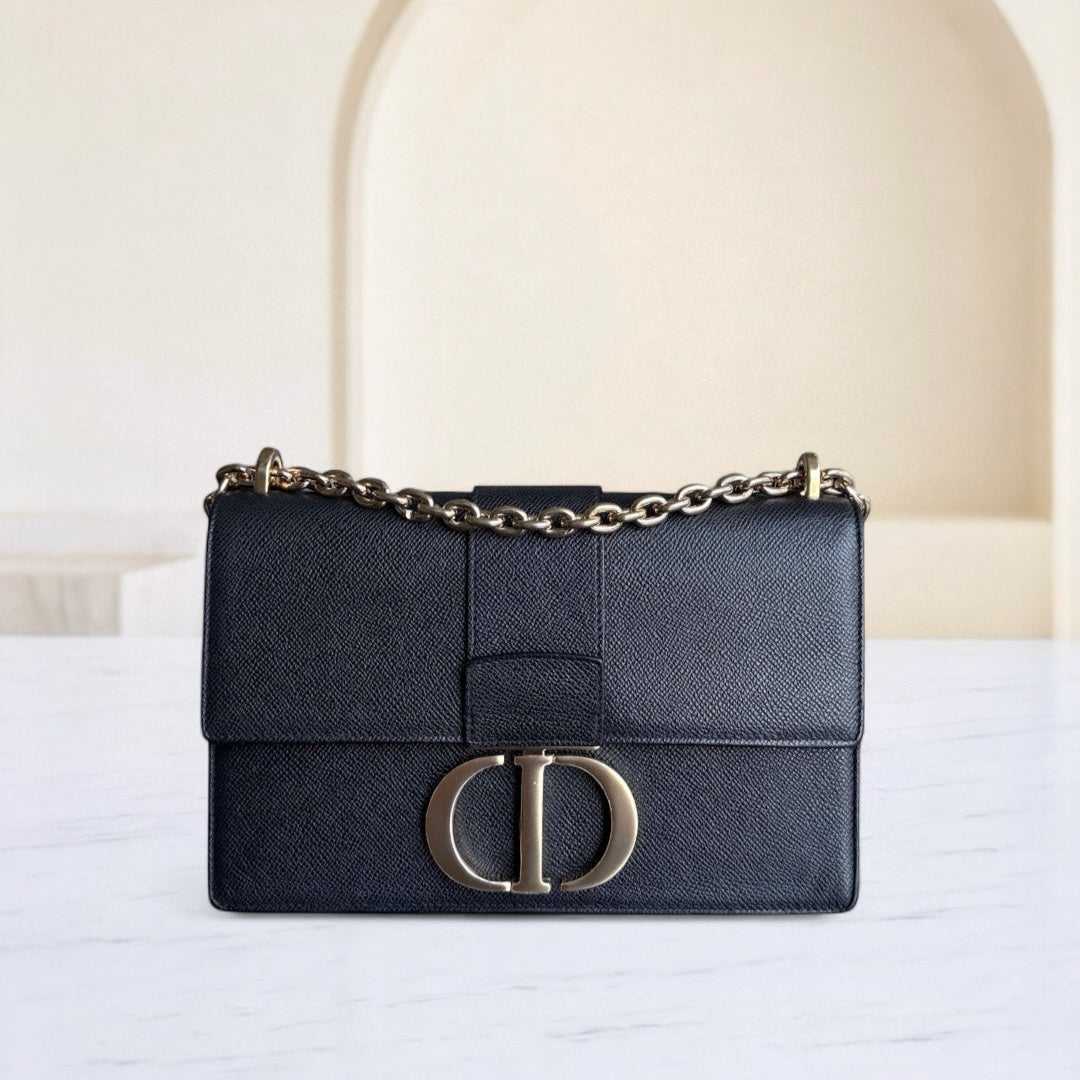 Black handbag with gold chain and clasp on a white surface
