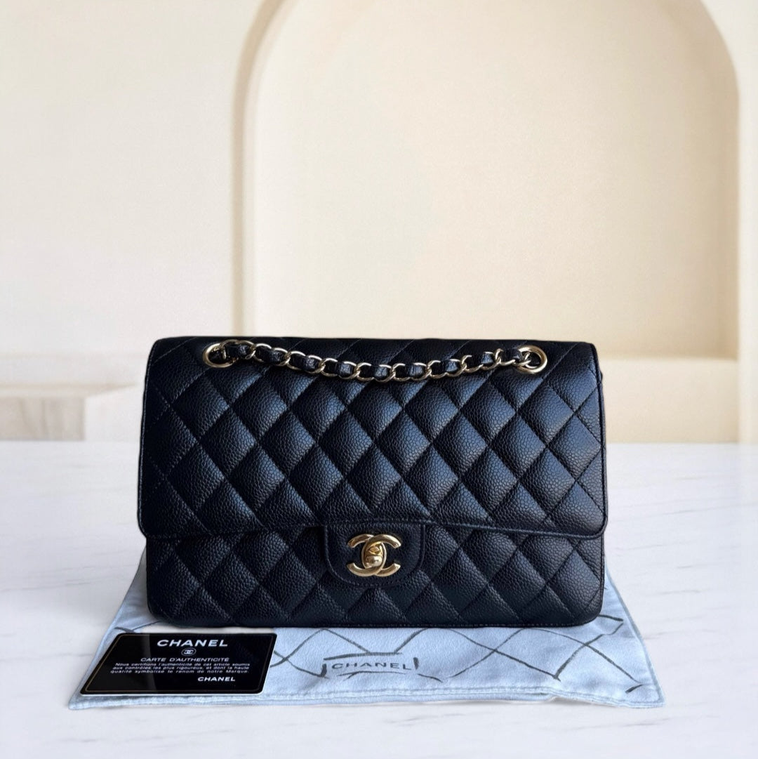Black quilted Chanel handbag on a white surface with a beige background