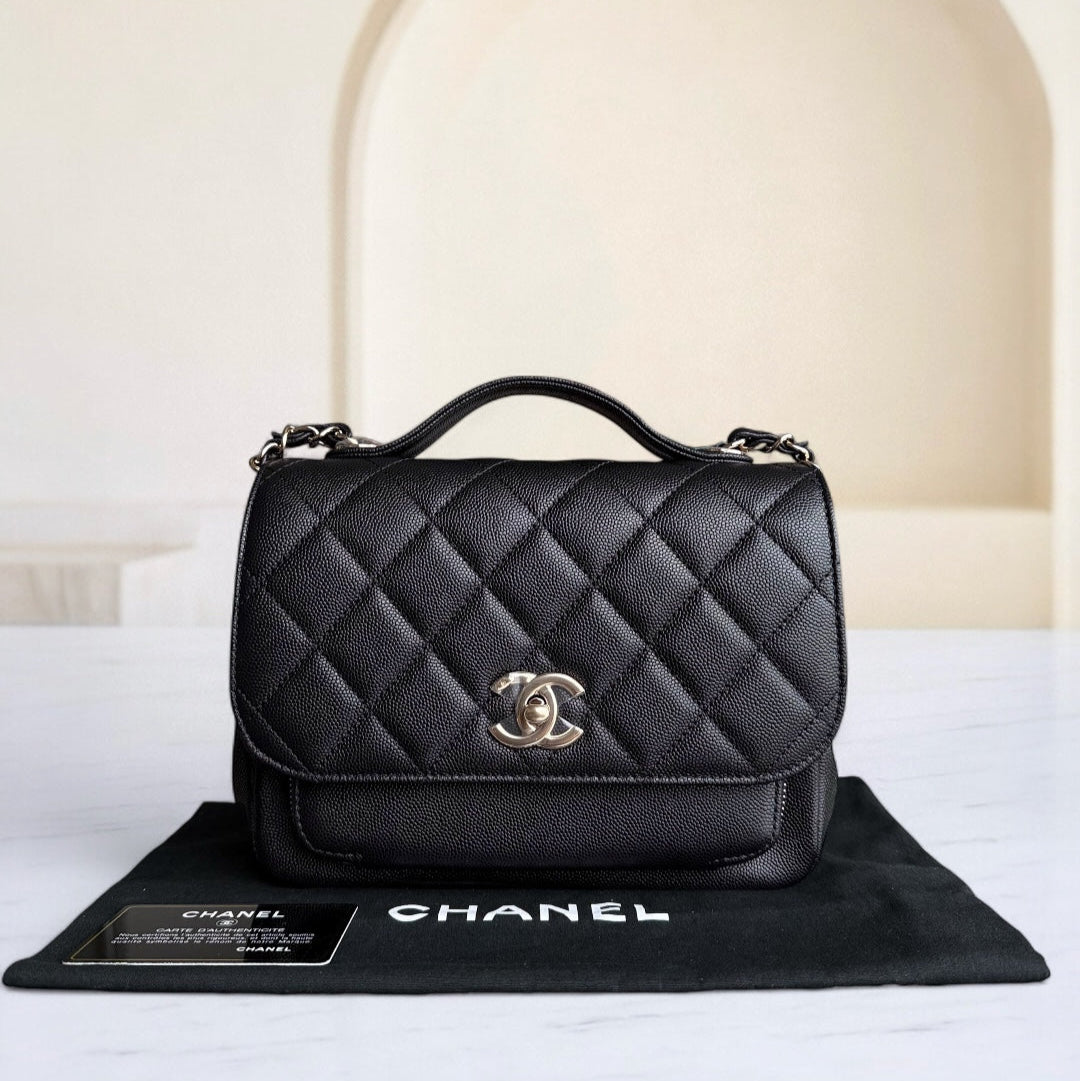 Black quilted Chanel handbag on a branded mat with a neutral background