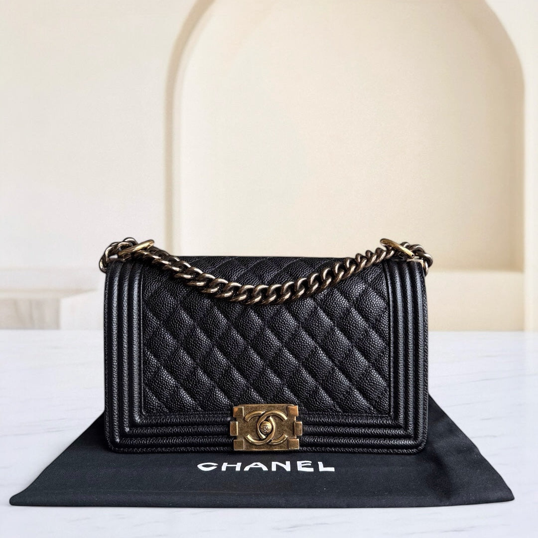 Black quilted Chanel handbag with gold chain on a white surface