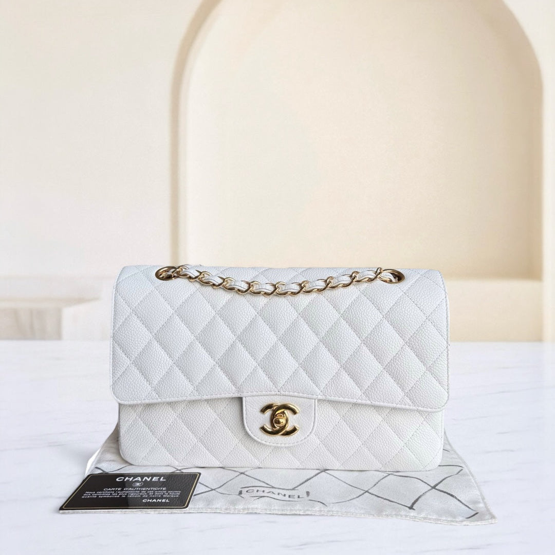 White quilted Chanel handbag with gold chain on a white surface