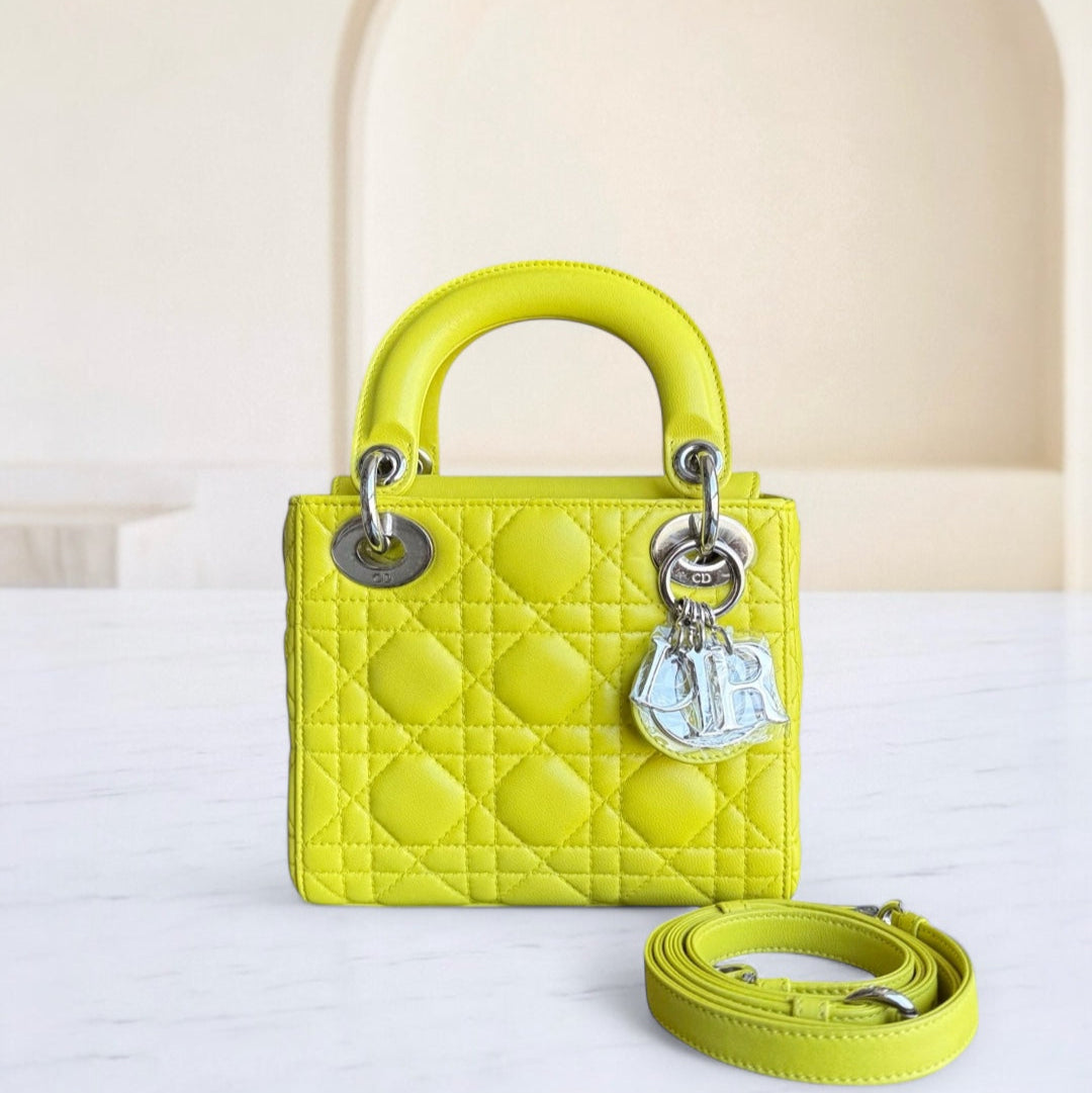 Yellow quilted handbag with silver hardware on a white surface