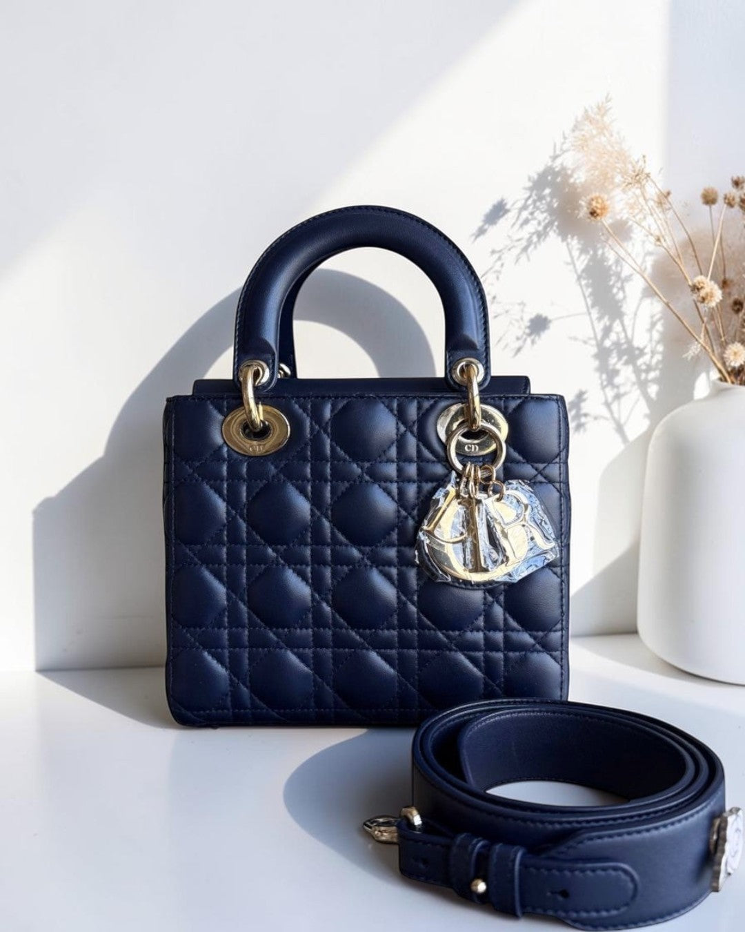 Navy blue quilted handbag with gold hardware on a white surface