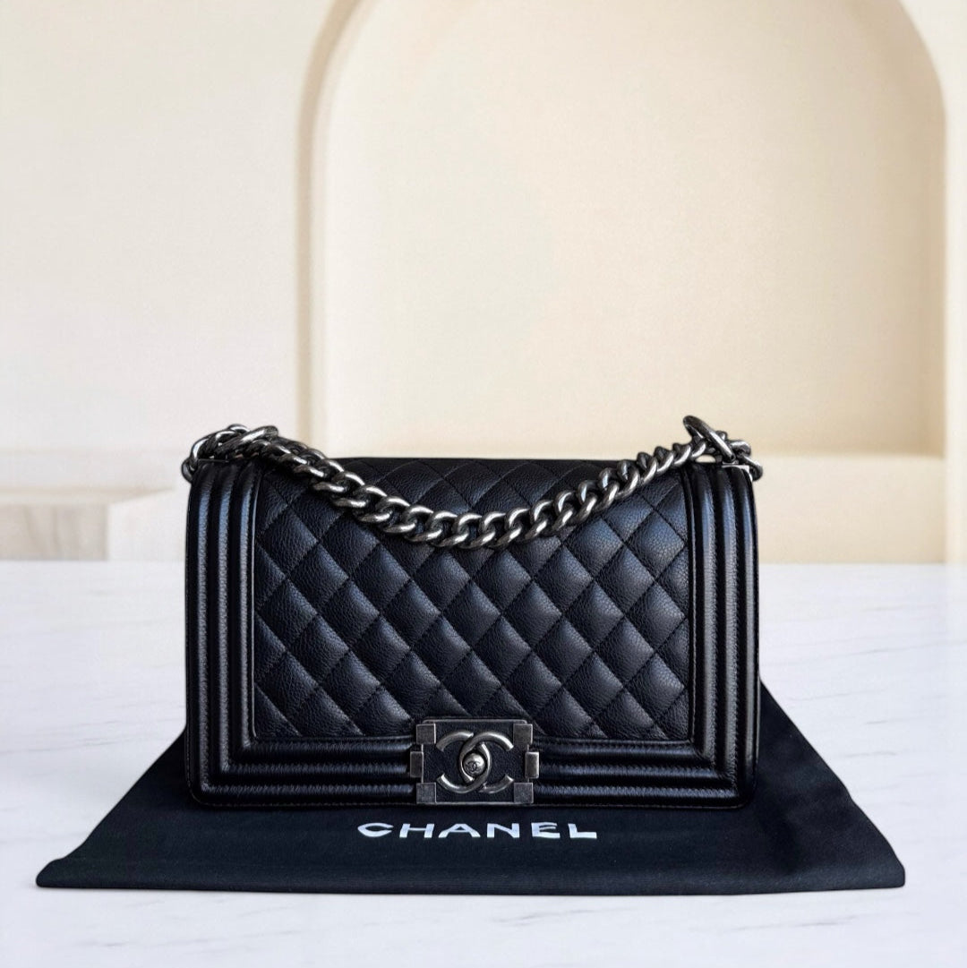 Black quilted Chanel handbag with chain detail on a white surface.