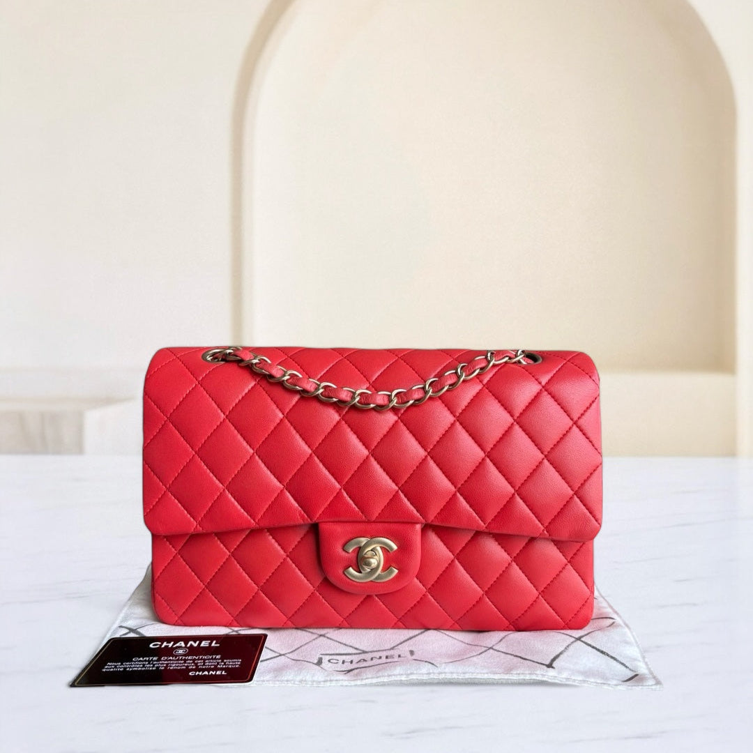 Red quilted handbag with gold chain on a white surface