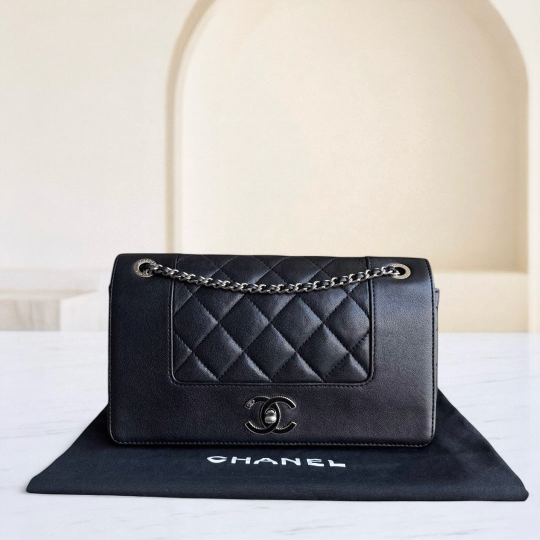 Black quilted Chanel handbag on a white surface with a neutral background