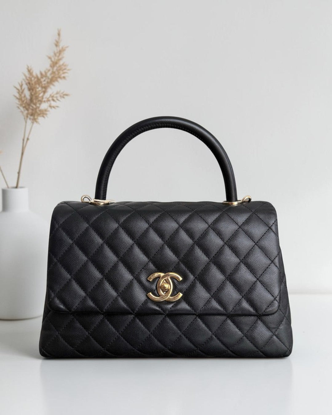 Luxury Evermore black quilted leather handbag with a top handle and gold CC logo hardware on a white surface.