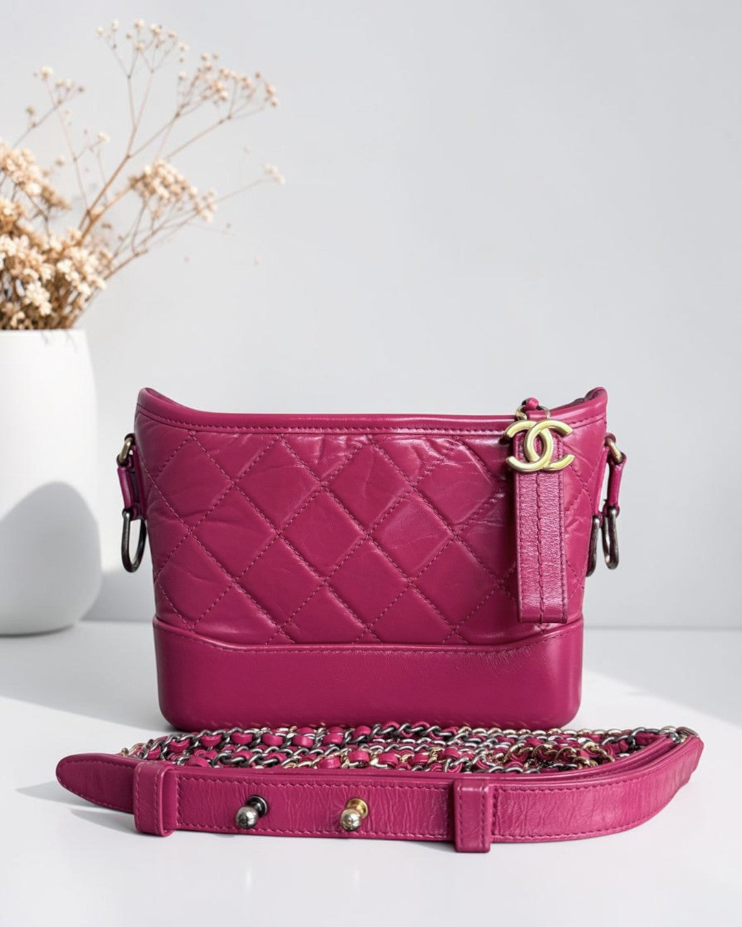 Luxury Evermore fuchsia quilted leather handbag with gold CC logo hardware and chain strap on a white surface