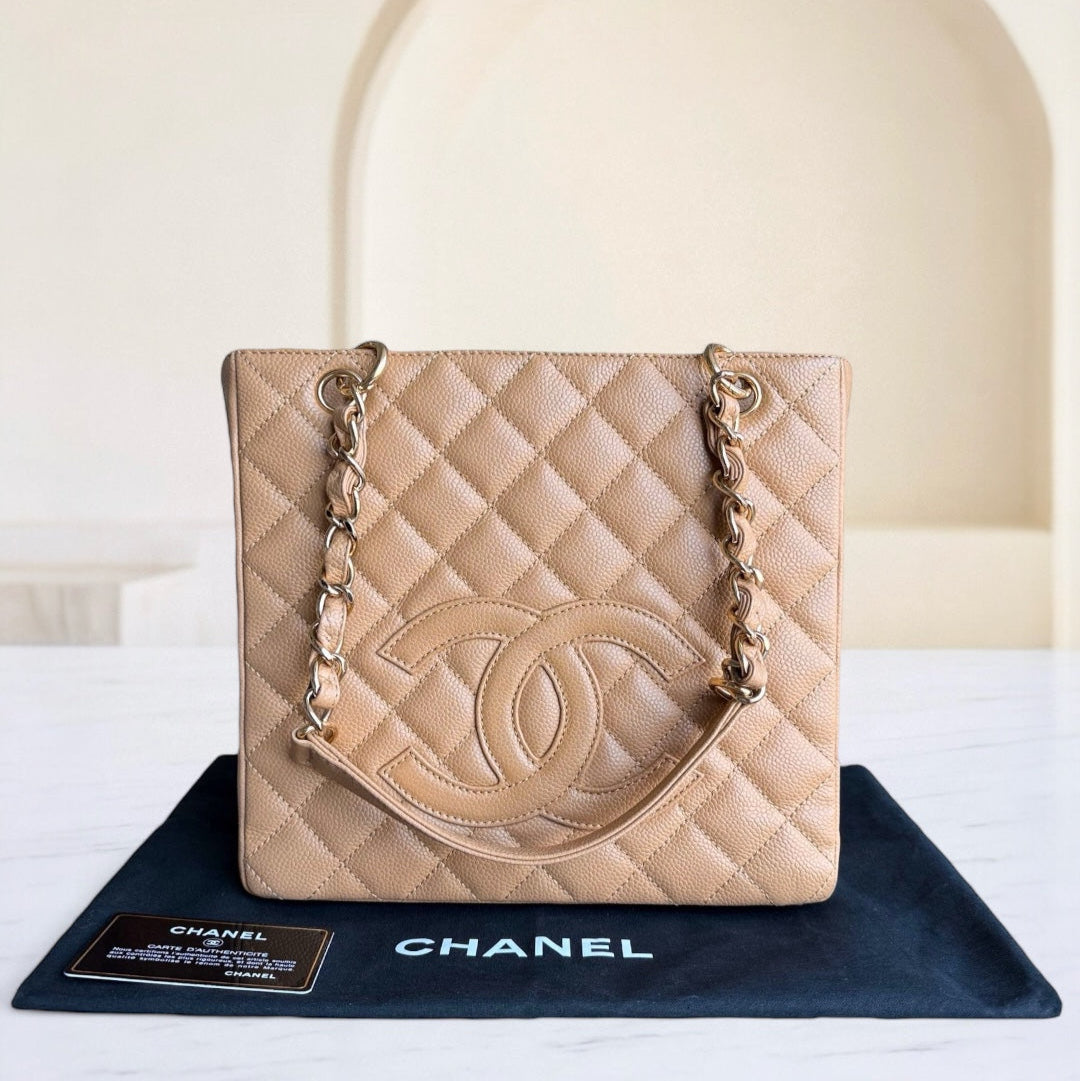 Beige quilted Chanel handbag on a black Chanel mat with a blurred background