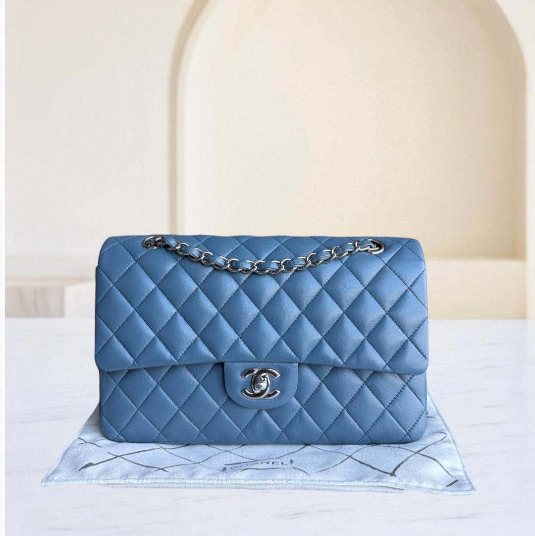 Blue quilted handbag with silver chain on a white surface