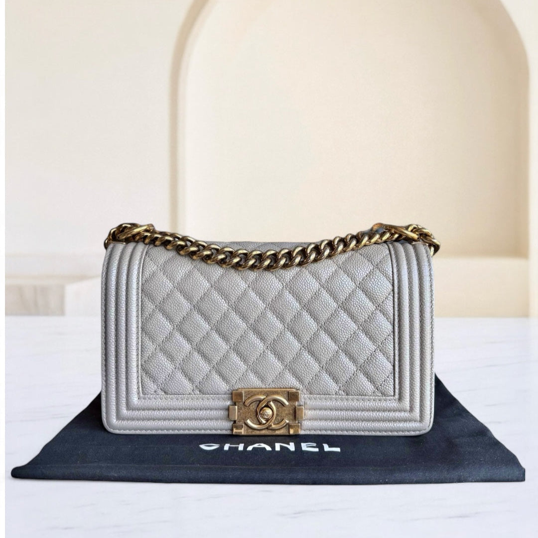 Chanel handbag with gold chain and clasp on a white surface with a blurred background