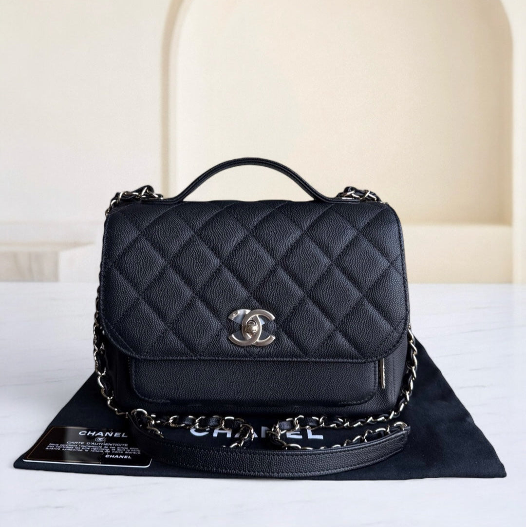 Black quilted Chanel handbag on a white surface with a neutral background