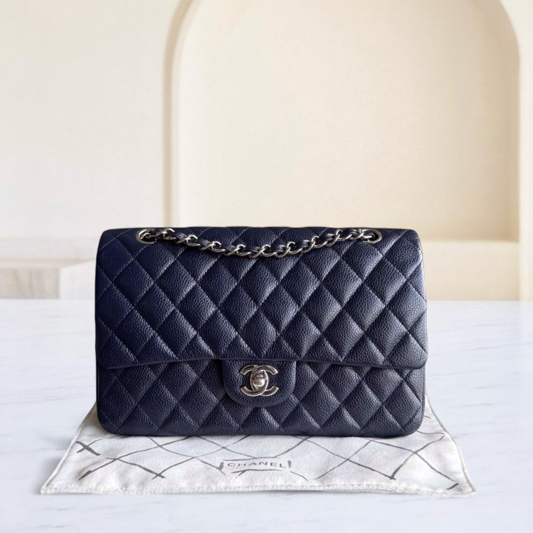 Navy blue quilted handbag with gold chain on a white surface