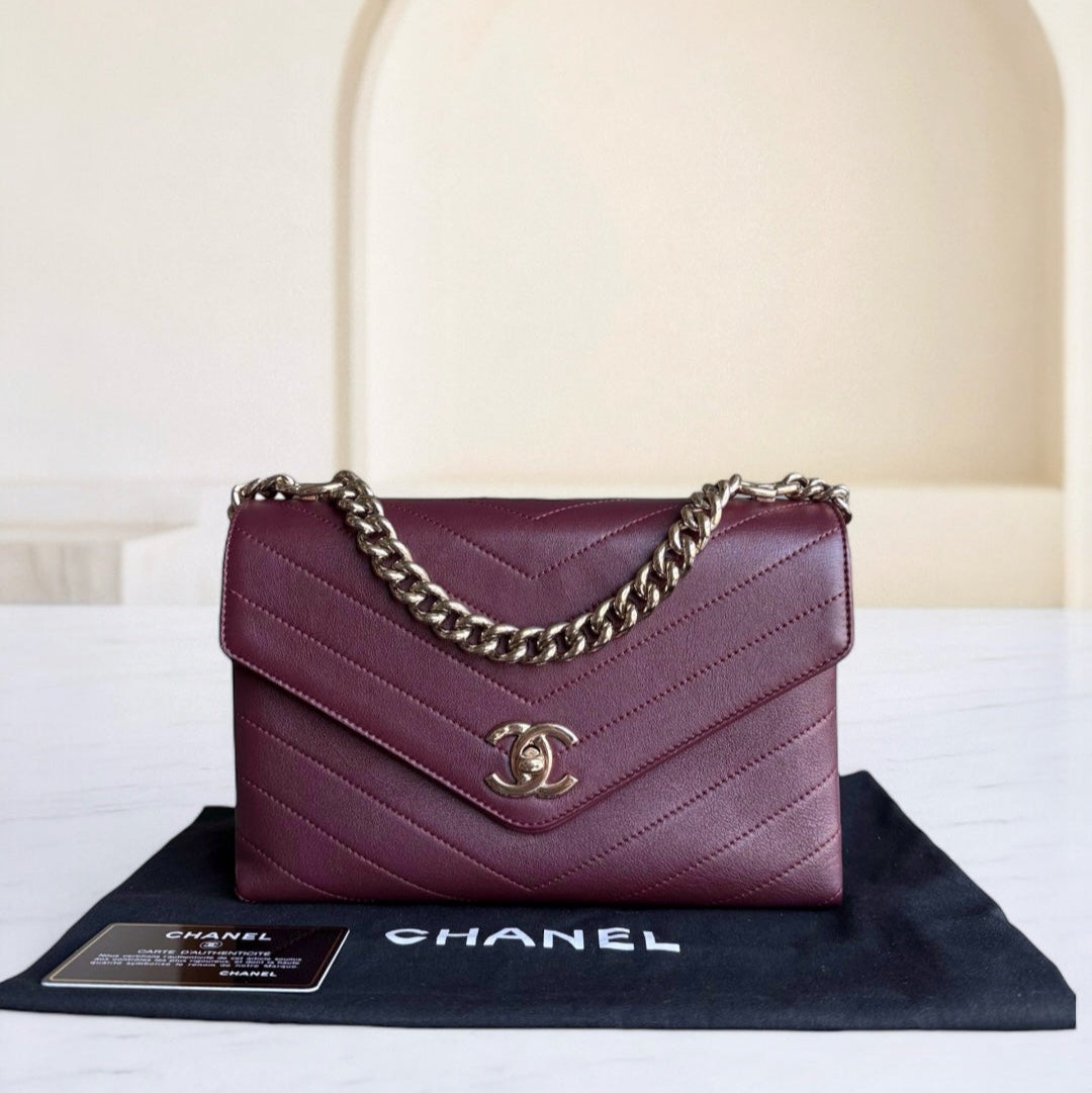 Chanel handbag with gold chain on a white surface with a blurred background
