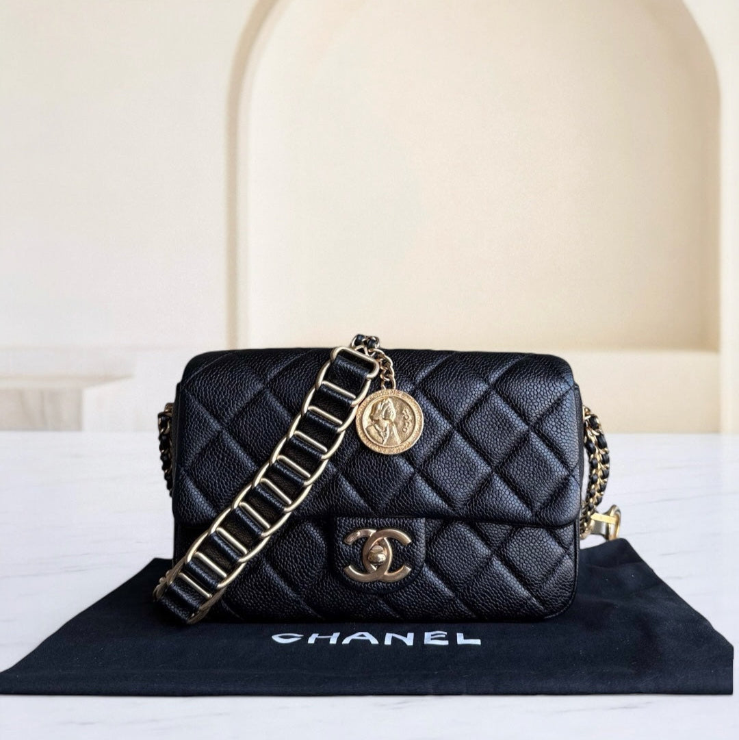Black quilted Chanel handbag with gold chain on a white surface