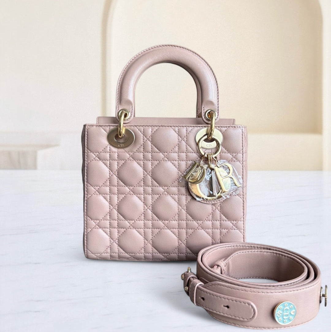 Pink quilted handbag with matching strap on a white surface