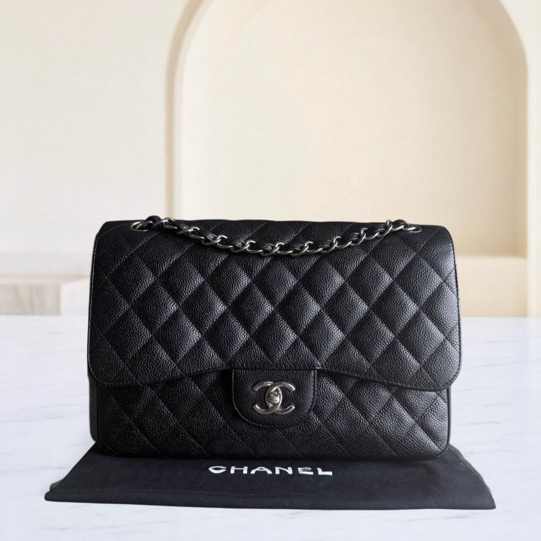 Black quilted Chanel handbag on a white surface with a neutral background