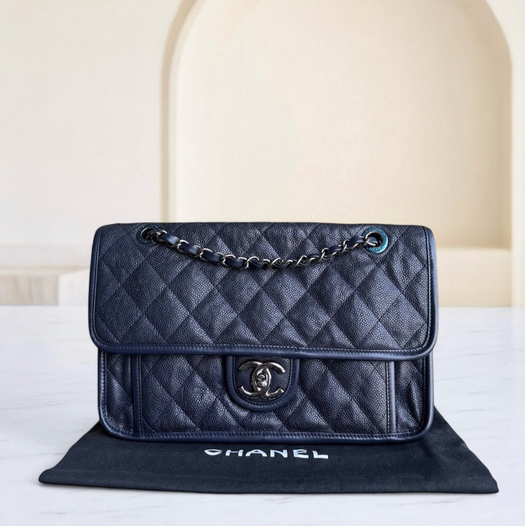 Navy blue quilted Chanel handbag on a white surface with a neutral background