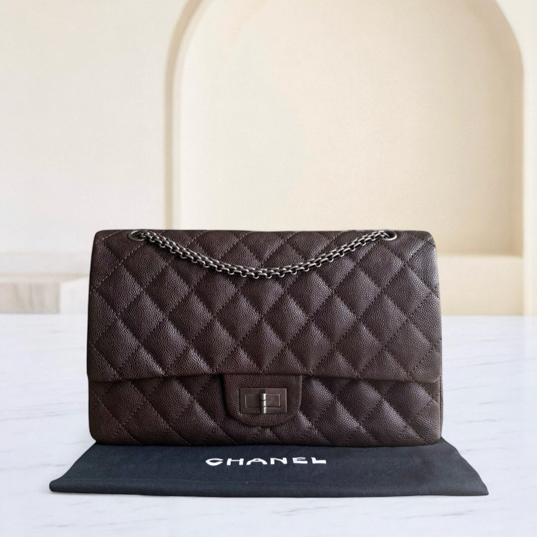Brown quilted Chanel handbag with chain strap on a white surface.