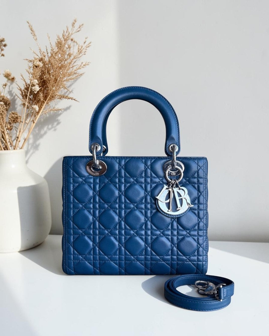 Blue quilted handbag with a brand logo on a white surface