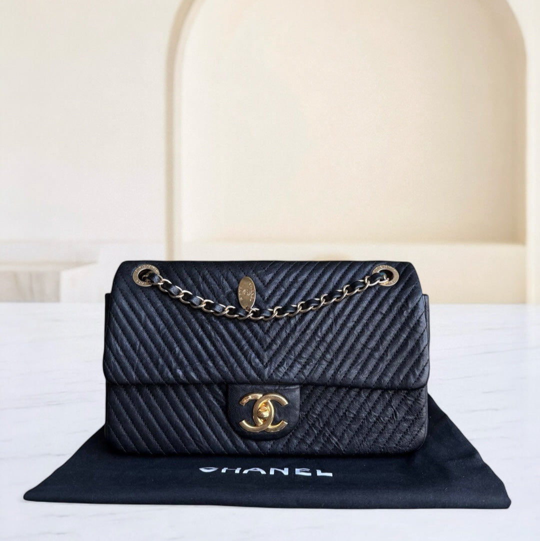 Black Chanel handbag with gold chain on a white surface with a beige background