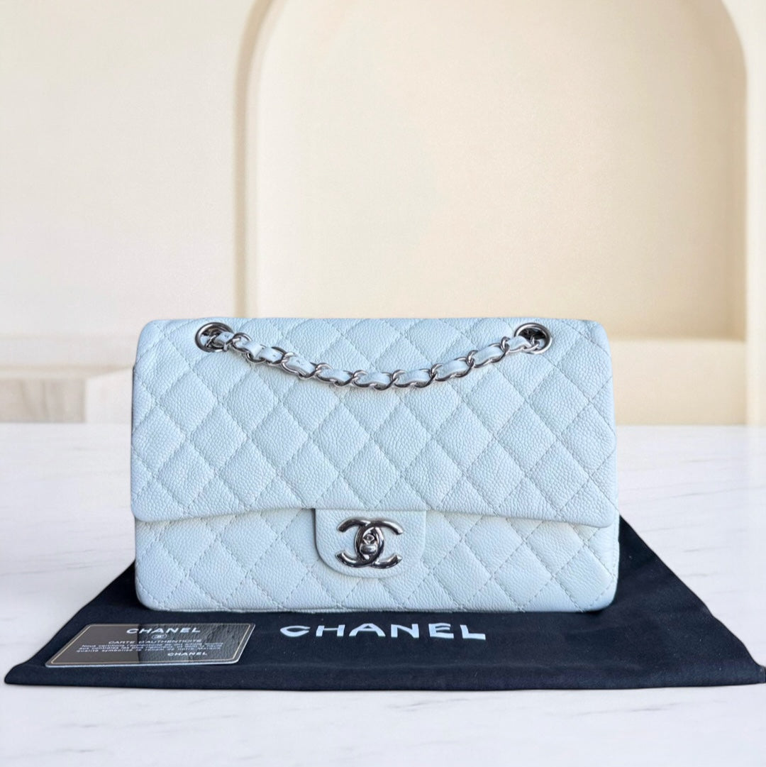 Light blue quilted Chanel handbag on a branded mat with a neutral background