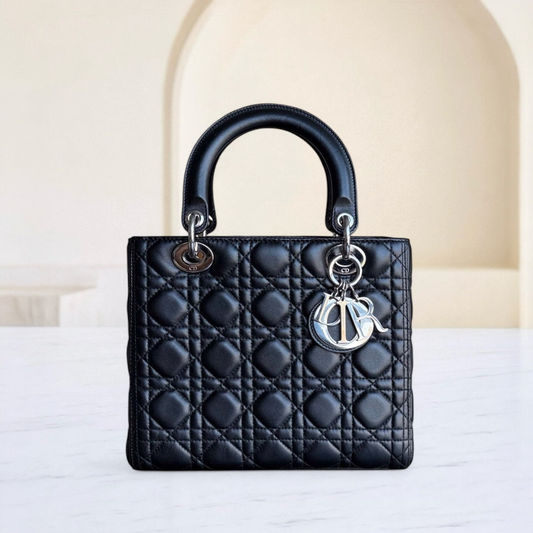 Black quilted handbag with a brand logo charm on a white surface.