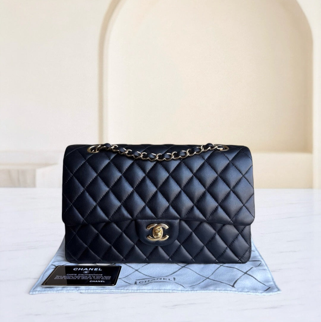 Black quilted Chanel handbag on a branded mat with a neutral background