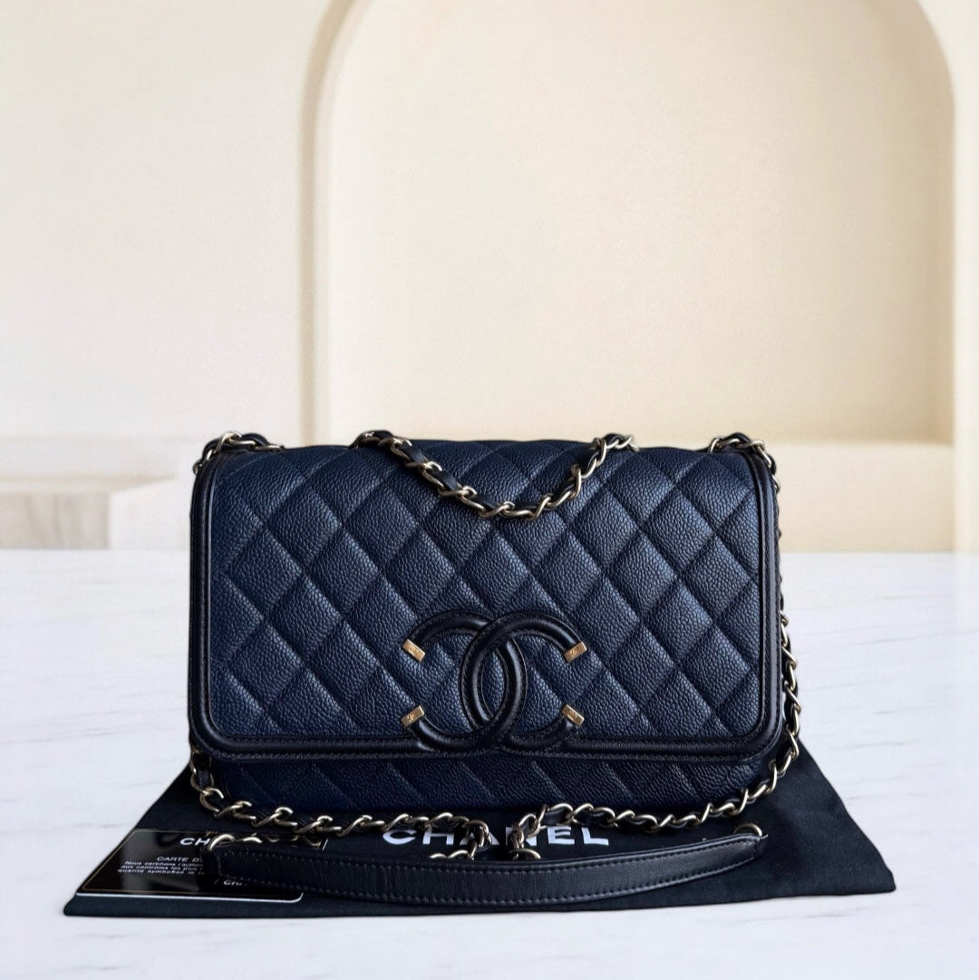 Blue quilted handbag with gold chain on a white surface