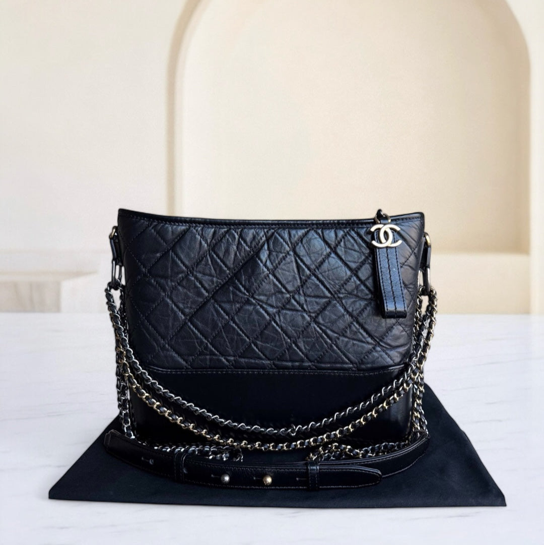 Black quilted handbag with chain detail on a white surface