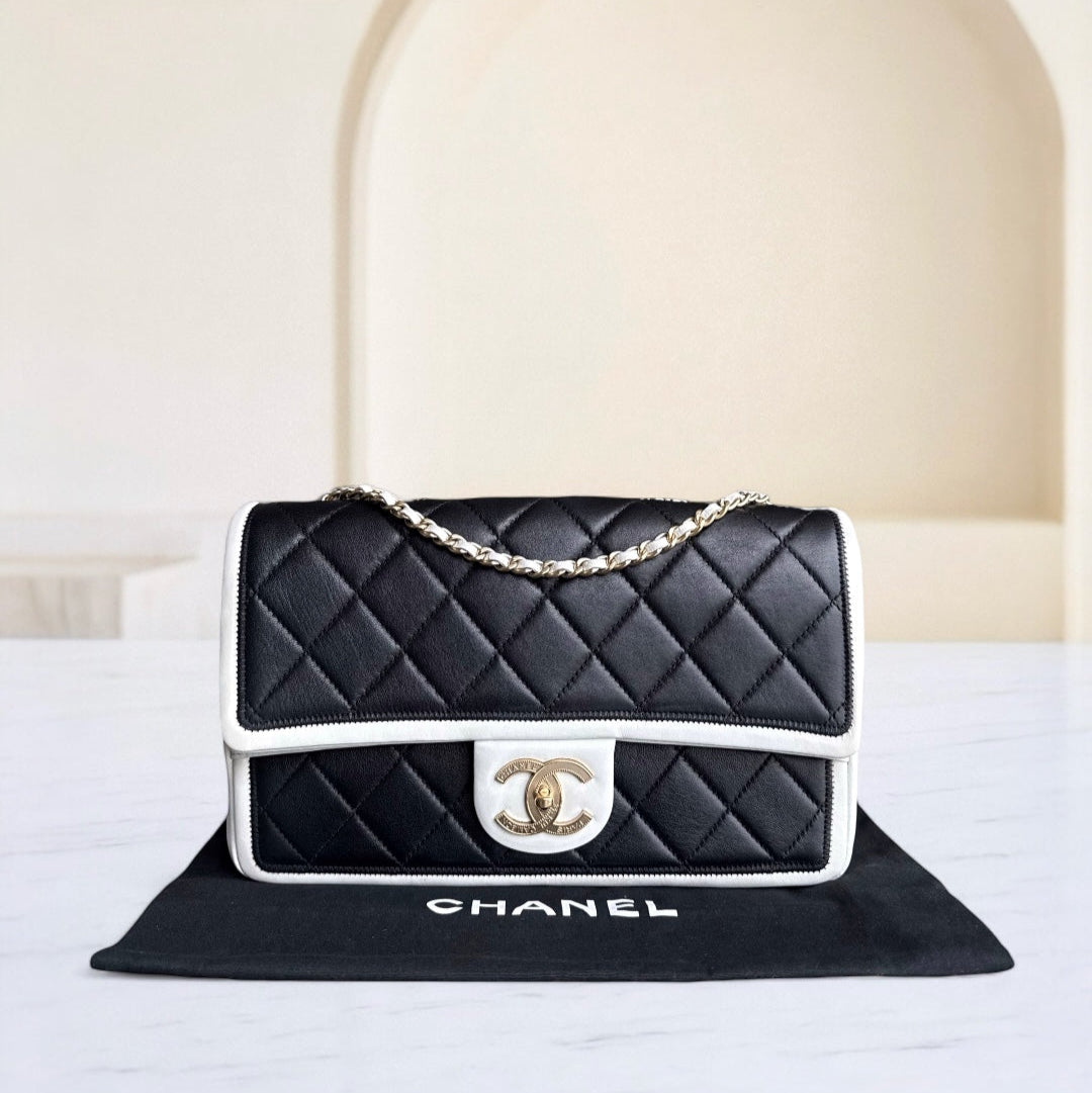 Black quilted Chanel handbag with gold chain on a white surface