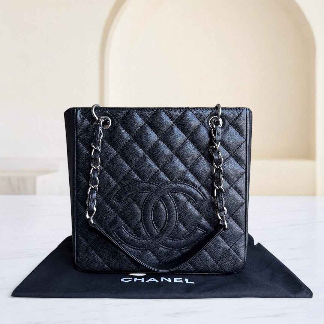 Black quilted Chanel handbag on a white surface with a neutral background